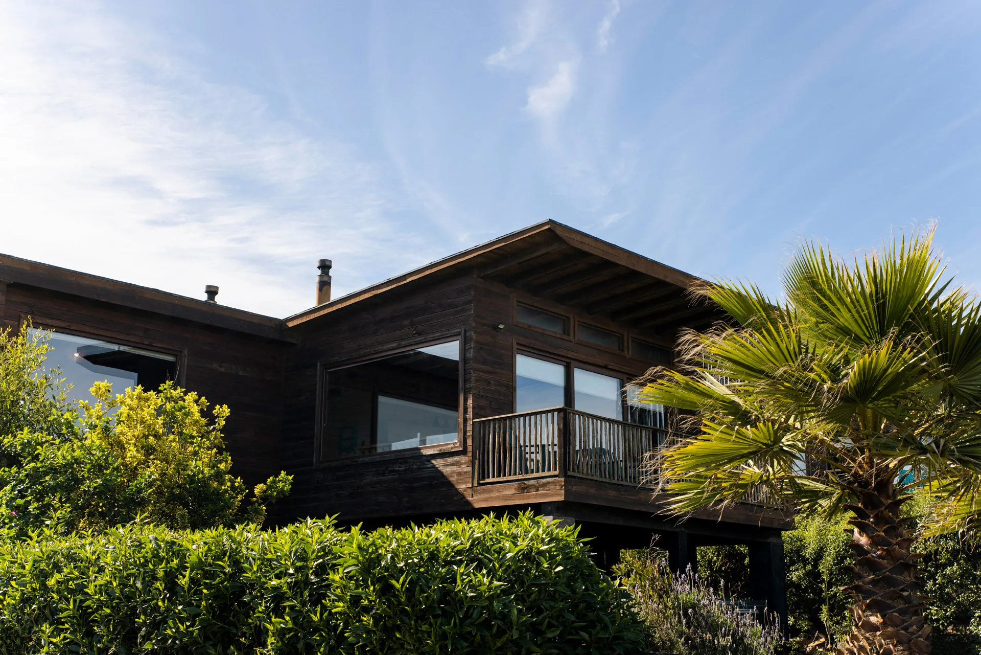 Cabaña con balcón y terraza, rodeada de vegetación
