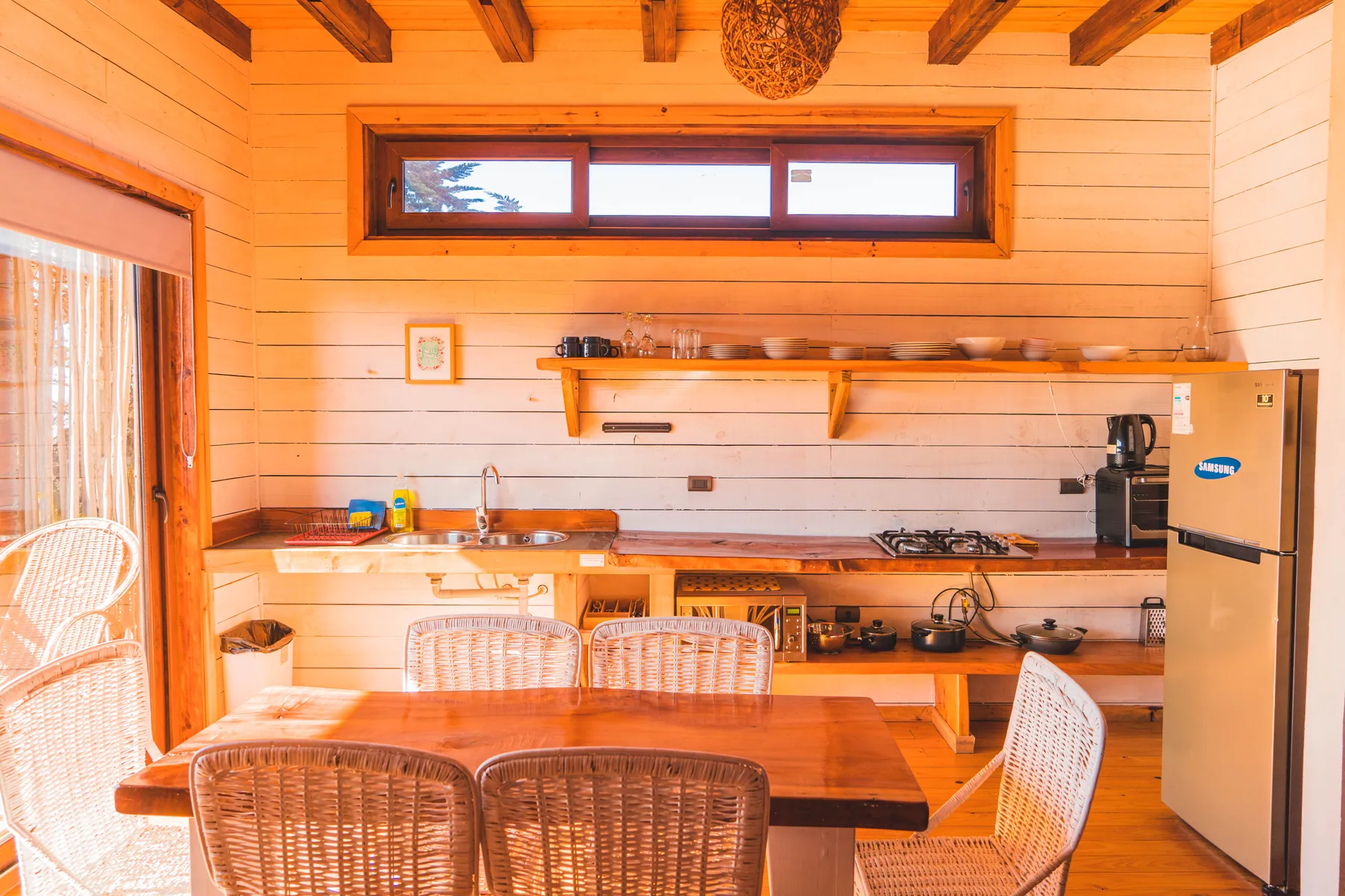 Cocina equipada y comedor de la cabaña Infiernillo, con mesa de madera y sillas de mimbre
