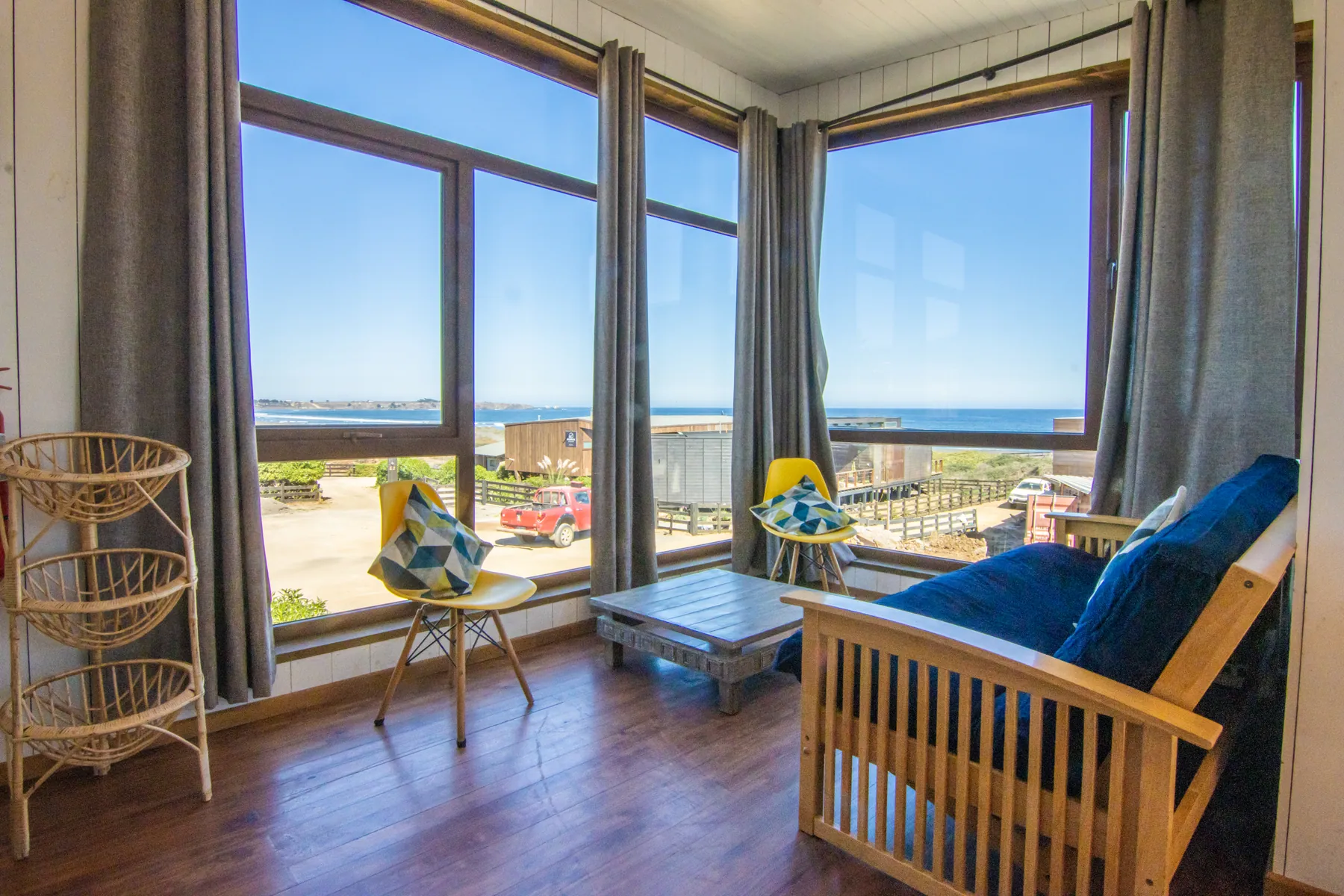 Living de la cabaña Los Morros con futón y ventanales de esquina, con vista al complejo y a la playa