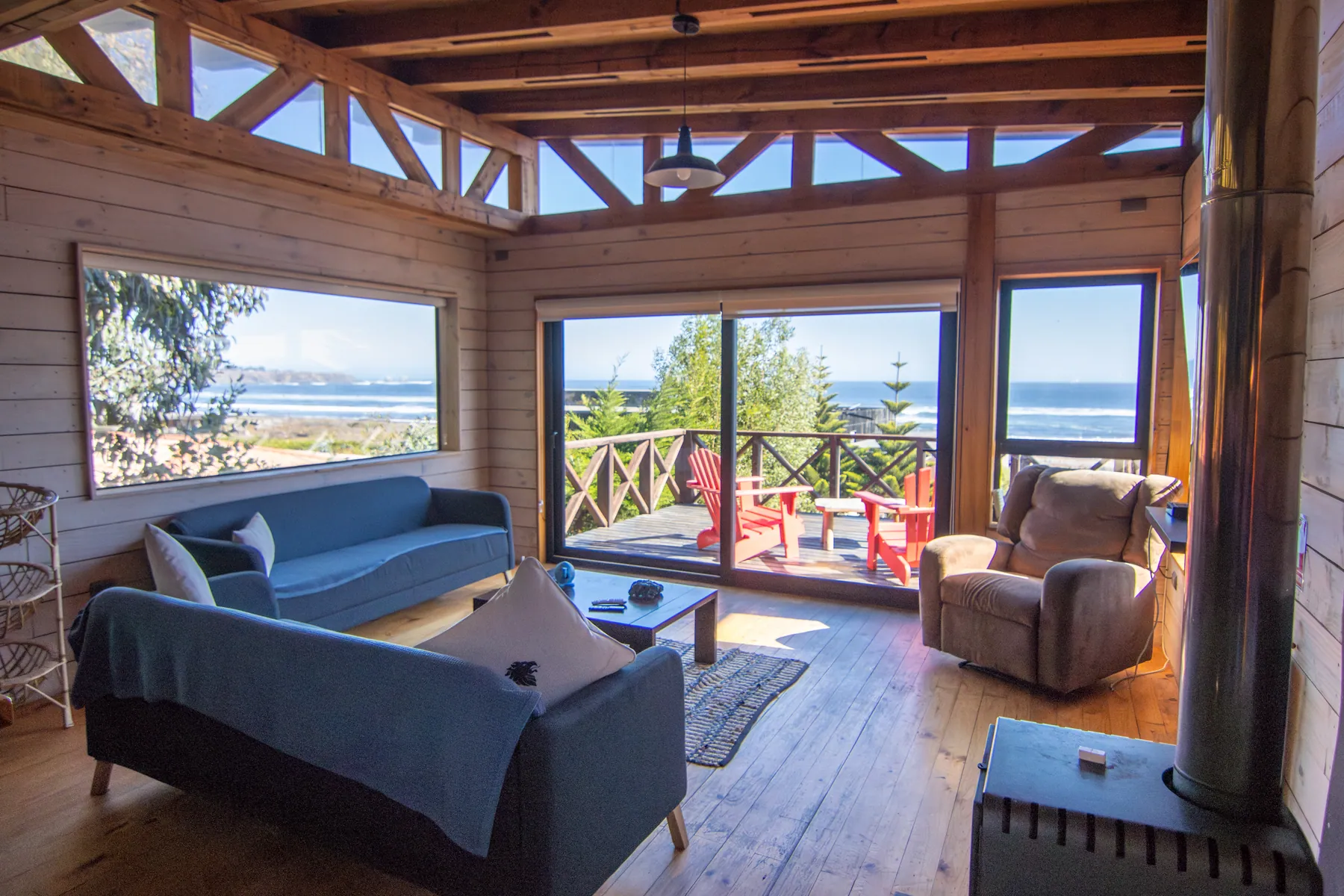 Living de la cabaña Tanume con dos sofás y sillón reclinable, frente al ventanal corredizo que da a la terraza